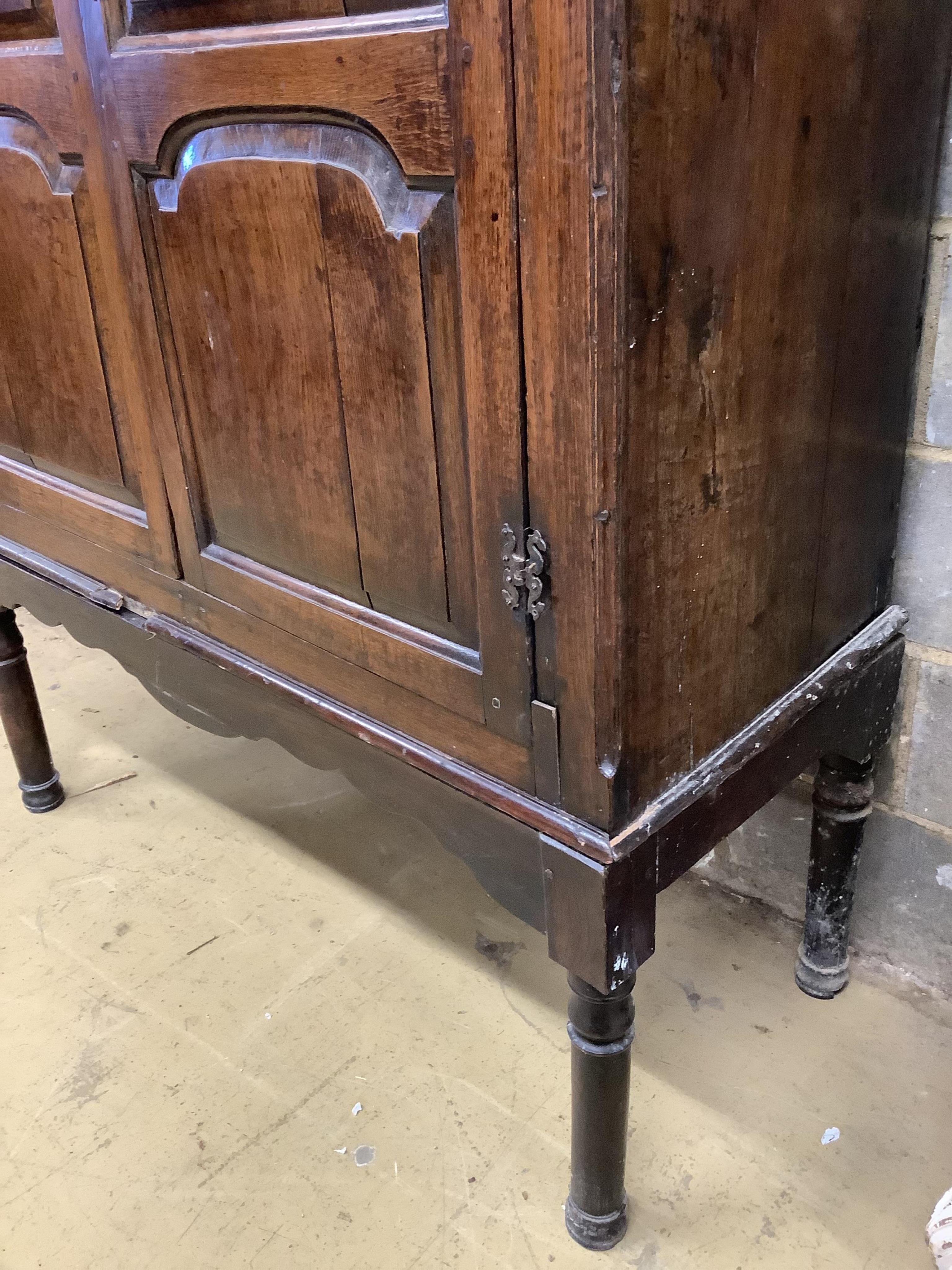 A mid 18th century carved oak cupboard, on associated stand, a.f., width 130cm, depth 55cm, height 178cm. Condition - poor